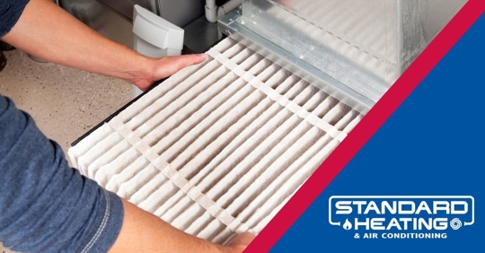 A person inserting an air filter into an HVAC unit