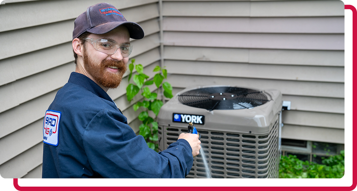 technician smiling while working on an AC unit